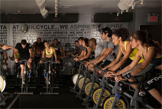 Some men and women ride dynamic bicycles together.