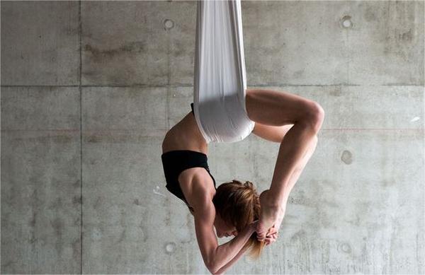 A woman wearing a black sportswear is doing yoga.